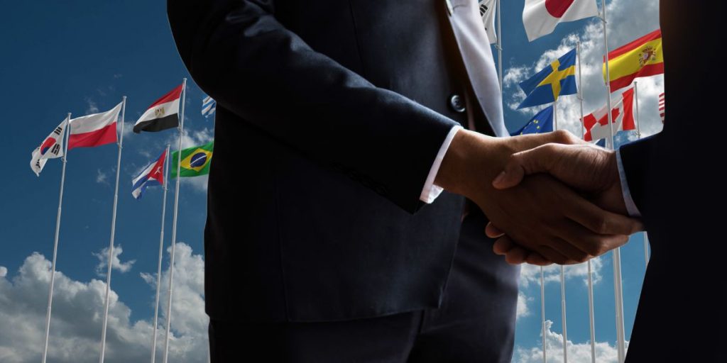 business men shaking hands with flags in background
