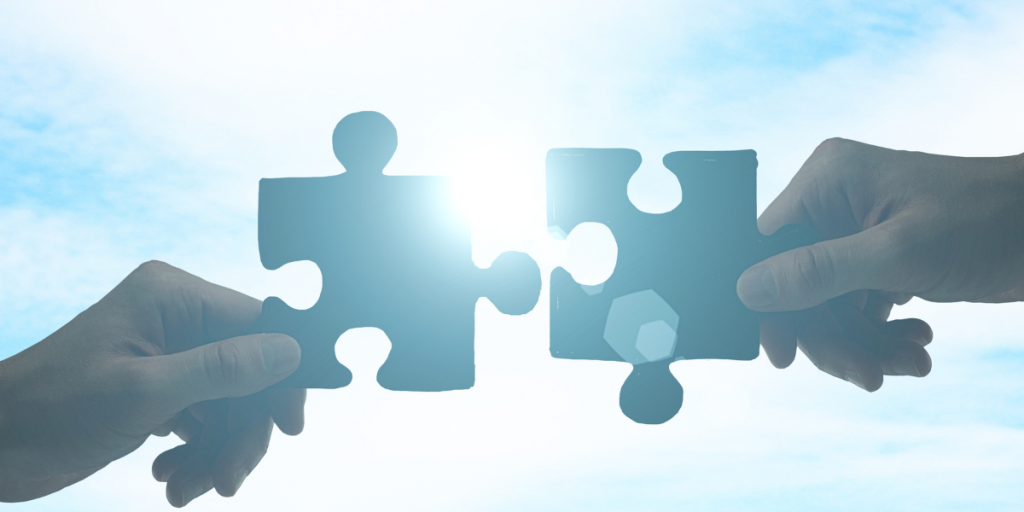 Two hands joining puzzle pieces together, representing strategic partnership